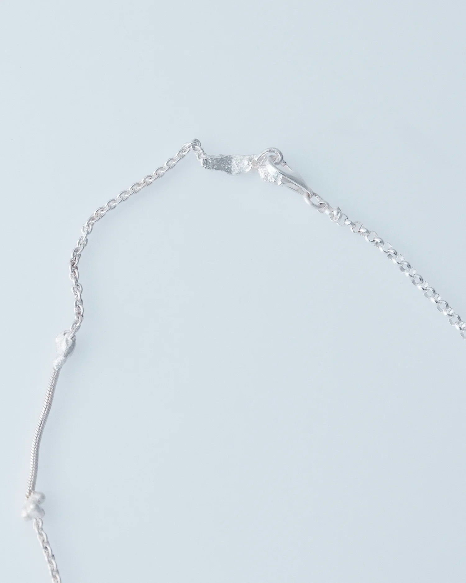 Silver necklace with a chain on a light gray background