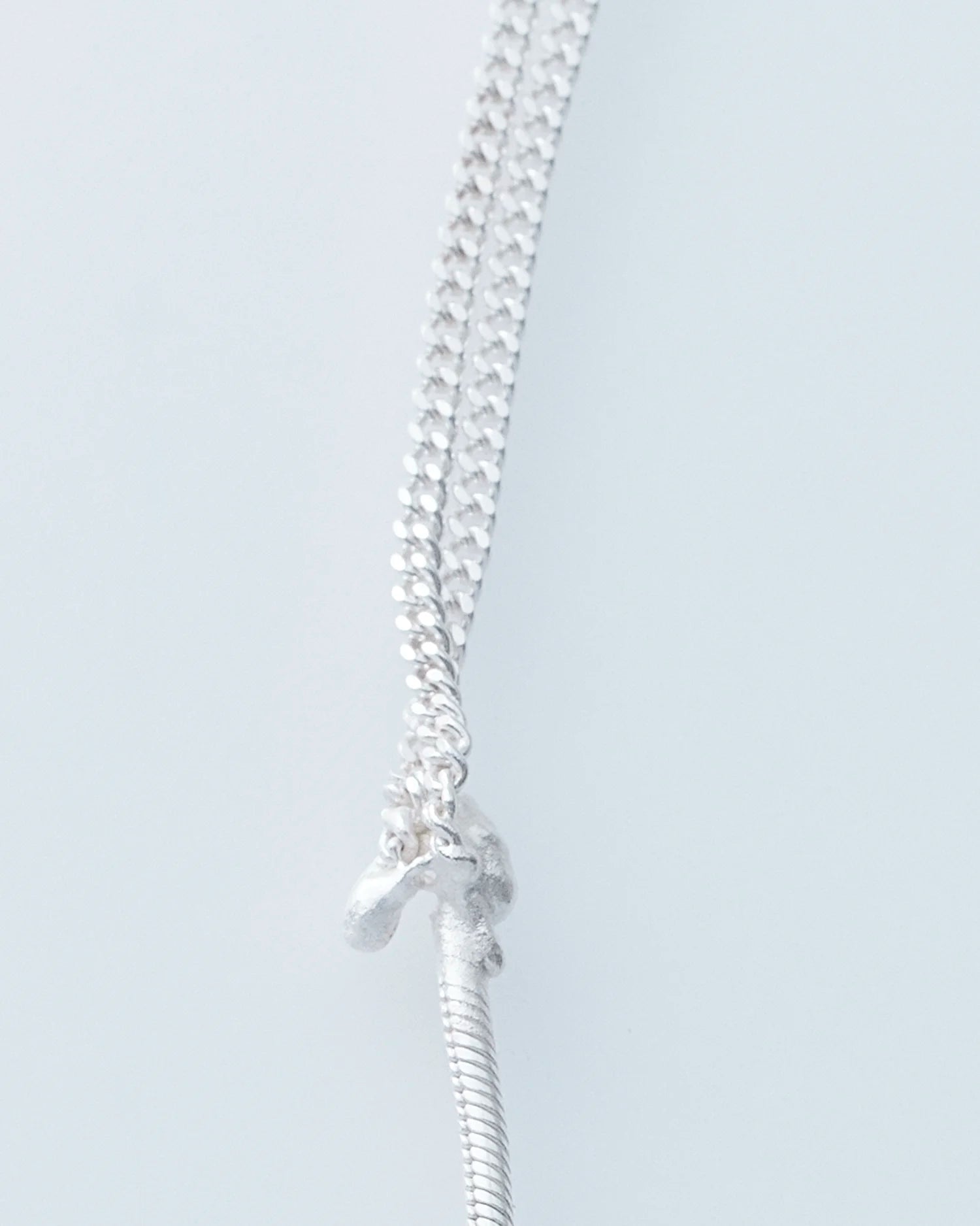 Silver chain necklace on a light gray background