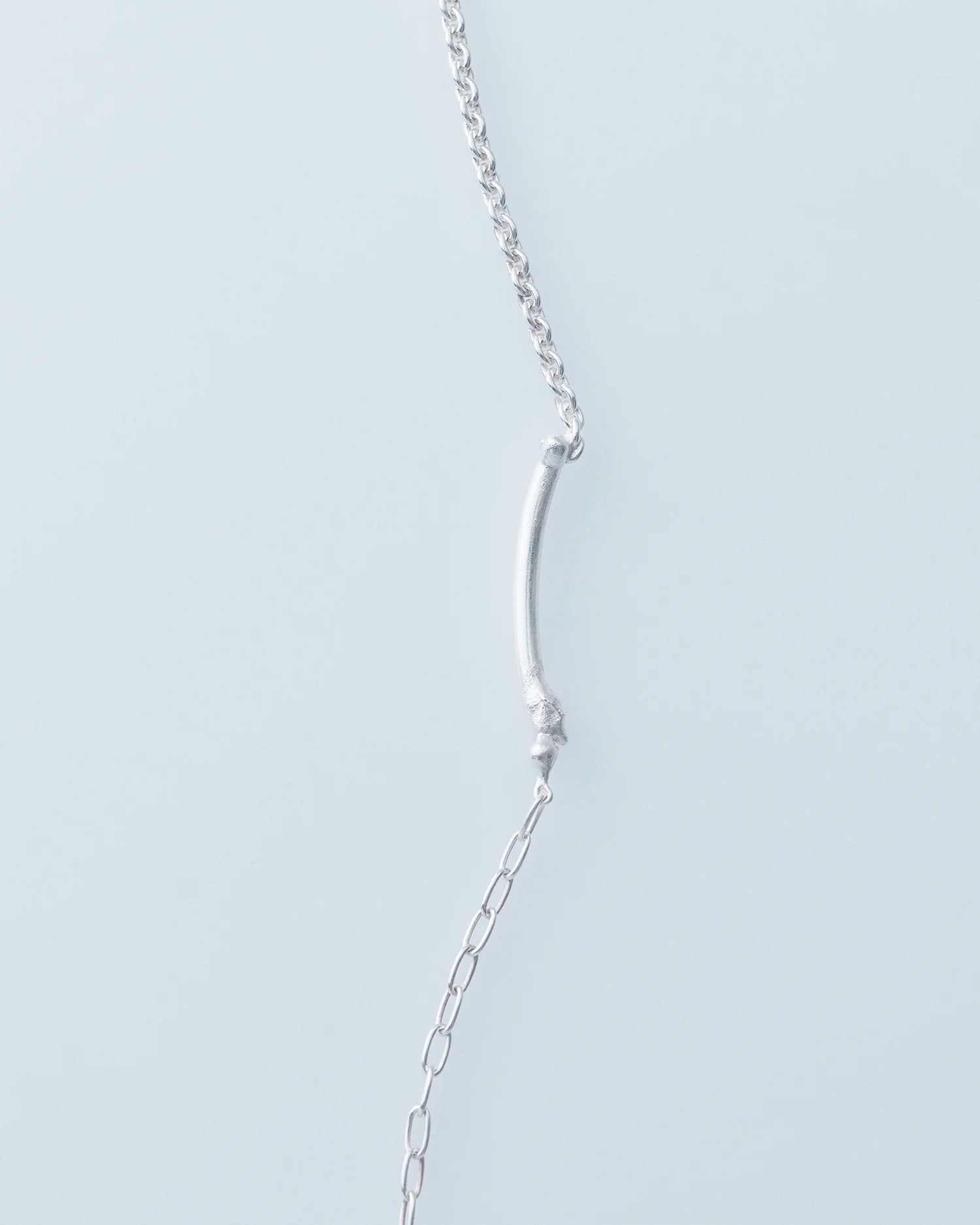 Silver chain necklace on a light gray background