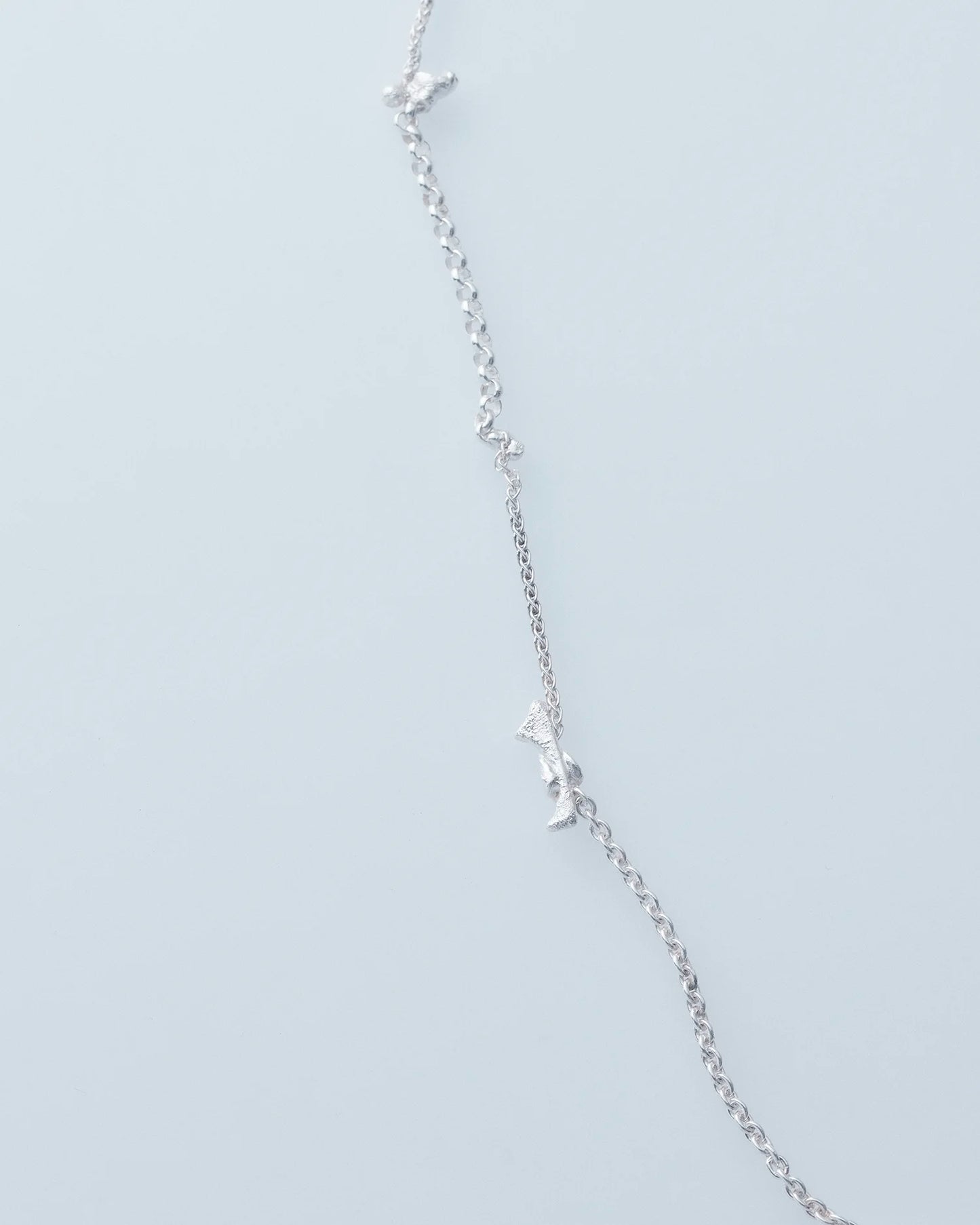 Silver necklace with small star-shaped pendants on a light gray background