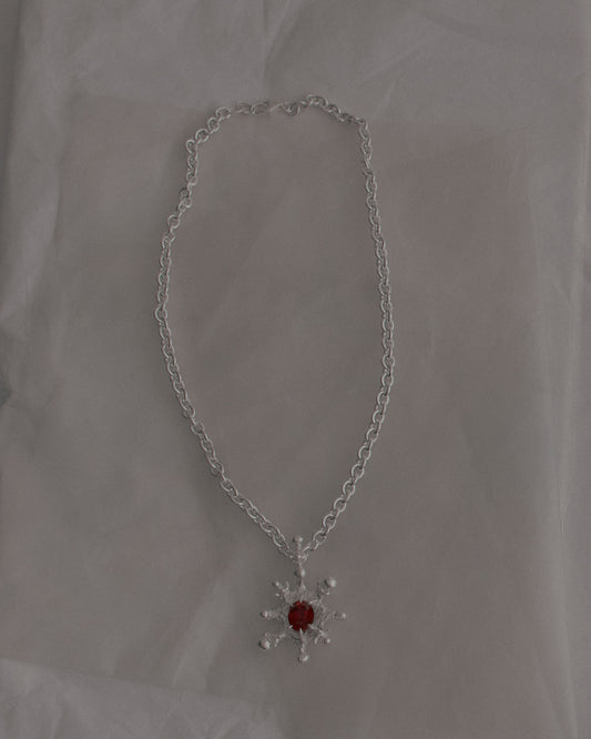 Necklace with a red gemstone pendant on a light gray background